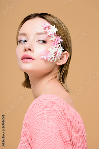 thoughtful girl with flowers on face isolated on beige