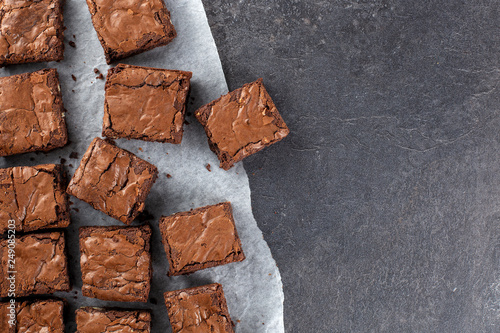 Chocolate brownie on paper on dark grey base top view flat lay