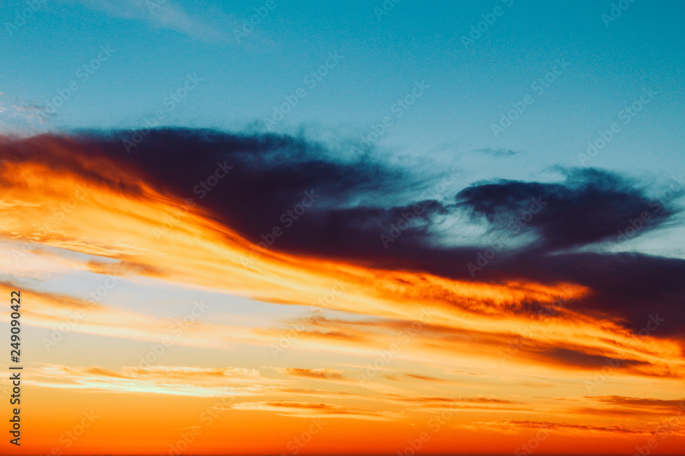 Background texture of dramatic cloud formations at sunset with an orange to purple gradient.