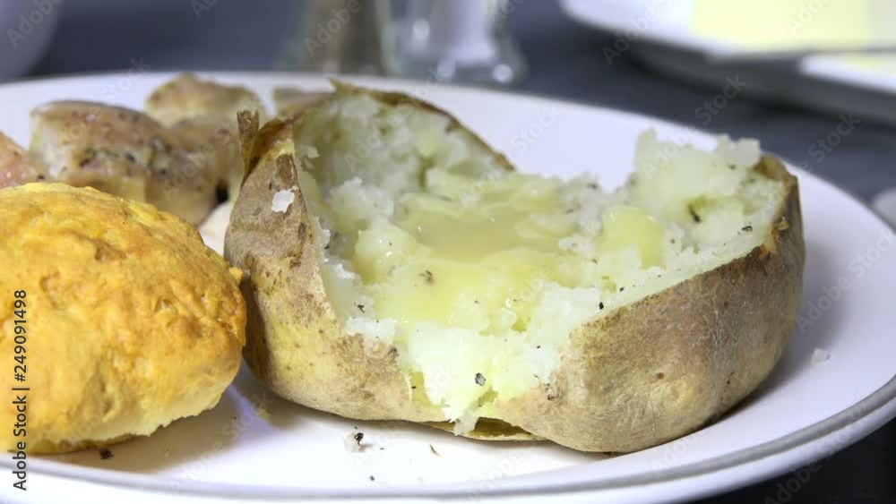 Spooning chicken gravy over a baked potato, slow motion Spooning chicken gravy over a baked potato, slow motion
