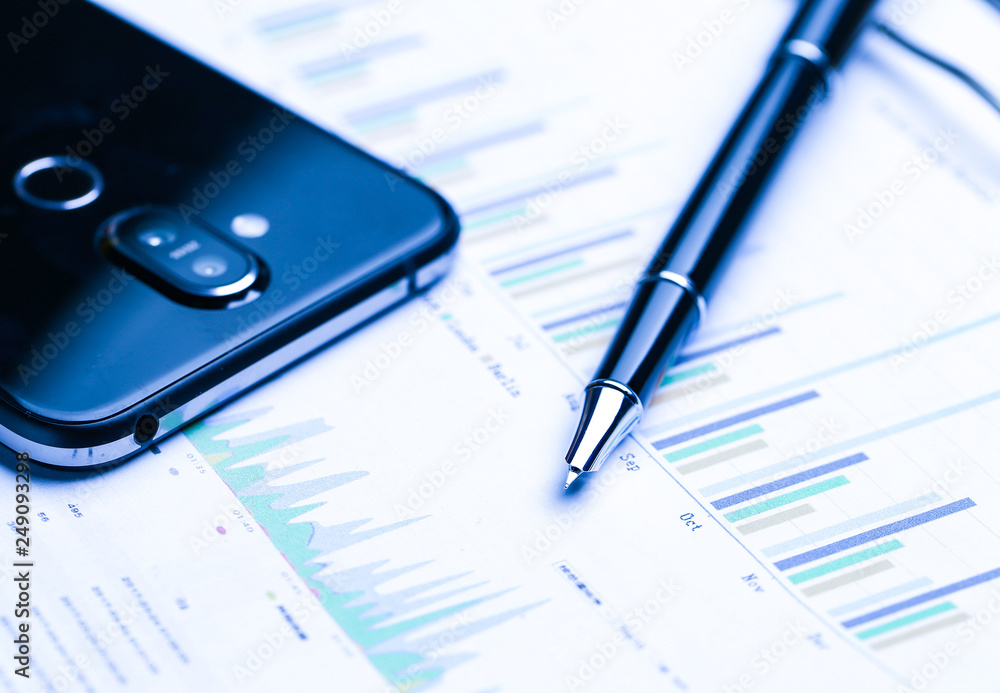 pen,cellphone and business statistics on wooden table pen,cellphone and business statistics on wooden table