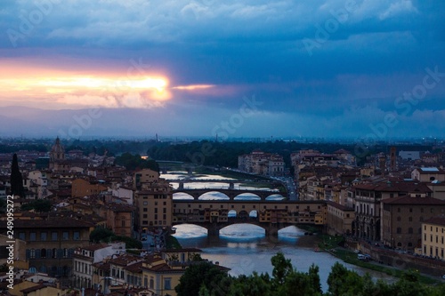 River Arno with bridge Ponte Vecchio in the evening view from Piazzale Michelangelo. Dramatic sunset dark blue sky. Amazing beautiful sunset. Florence, Italy.