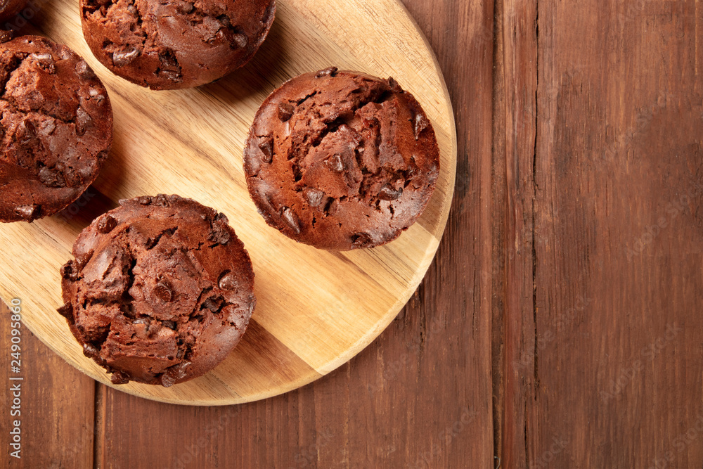 Fototapeta premium An overhead photo of chocolate muffins on a dark rustic wooden background with a place for text