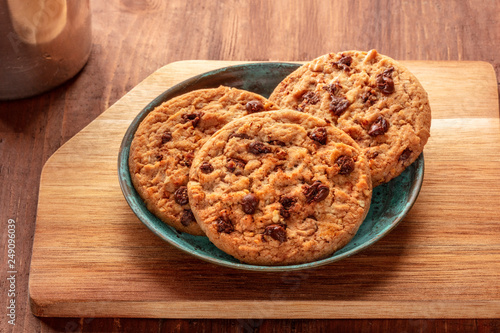 A closeup of chocolate chip cookies on a plate on a rustic wooden background