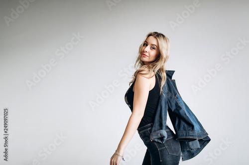 Portrait of a beautiful fashion woman, blonde, jeans, gray background