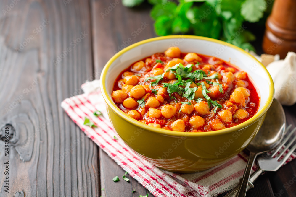 Spicy Chickpea curry Chana Masala in bowl on dark wooden table. Traditional Indian dish. Selective focus. Spicy Chickpea curry Chana Masala in bowl on dark wooden table. Traditional Indian dish. Selective focus.