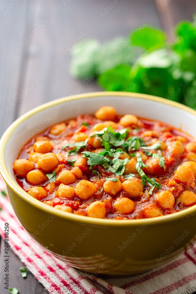 Spicy Chickpea curry Chana Masala in bowl on dark wooden table. Traditional Indian dish. Selective focus.