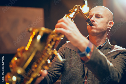 Photography Young talented saxophone player plauing his instrument and standing in home studio