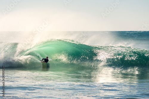 man surfing the barrel of a wave at sunset