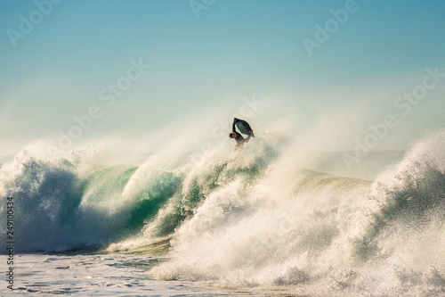 Surfer jumps a powerful and big wave at sunset © Raul Mellado