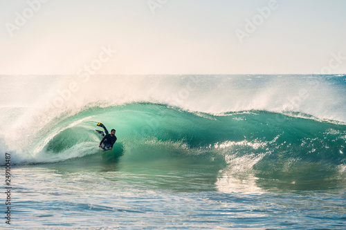 surfer riding a perfect barrel of a wave at sunset