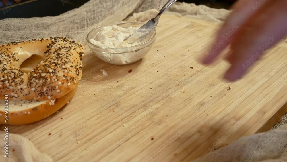 Putting bagels onto a wooden board with cream cheese Putting bagels onto a wooden board with cream cheese
