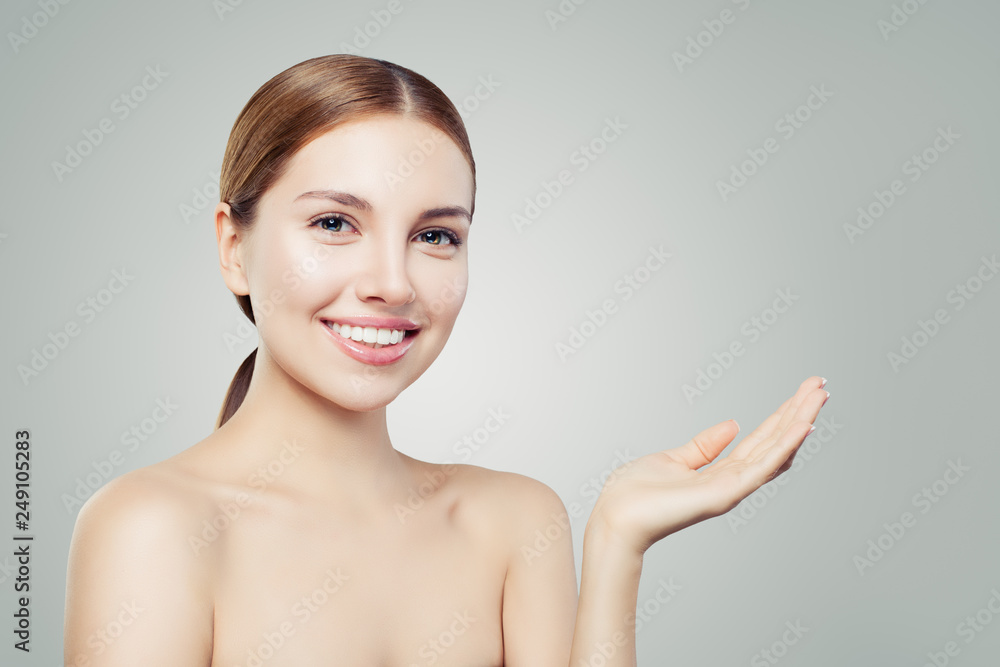 Pretty woman smiling and showing empty open hand. Facial treatment, face lifting, anti aging and skin care cosmetics concept. Pretty woman smiling and showing empty open hand. Facial treatment, face lifting, anti aging and skin care cosmetics concept.