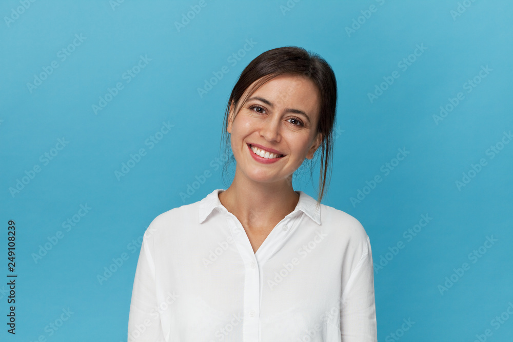 Portrait of a pretty smiling woman with white shirt posing isolated on a blue background Portrait of a pretty smiling woman with white shirt posing isolated on a blue background