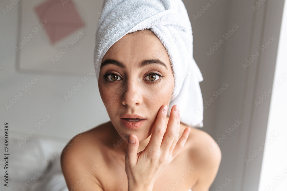 Photo closeup of attractive woman wrapped in white towel, standing in room after shower Photo closeup of attractive woman wrapped in white towel, standing in room after shower