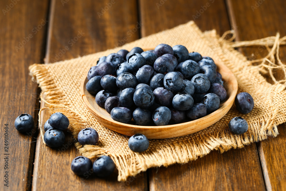 Fresh blueberries in wooden plate on a wooden table Fresh blueberries in wooden plate on a wooden table