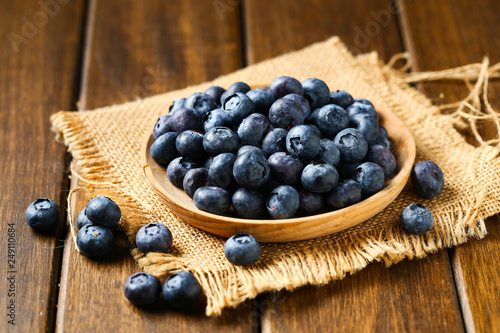 Fresh blueberries in wooden plate on a wooden table