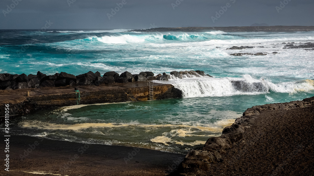 Waves jumping on dock of the fishing cove of La Santa in Lanzarote during a storm. Waves jumping on dock of the fishing cove of La Santa in Lanzarote during a storm.