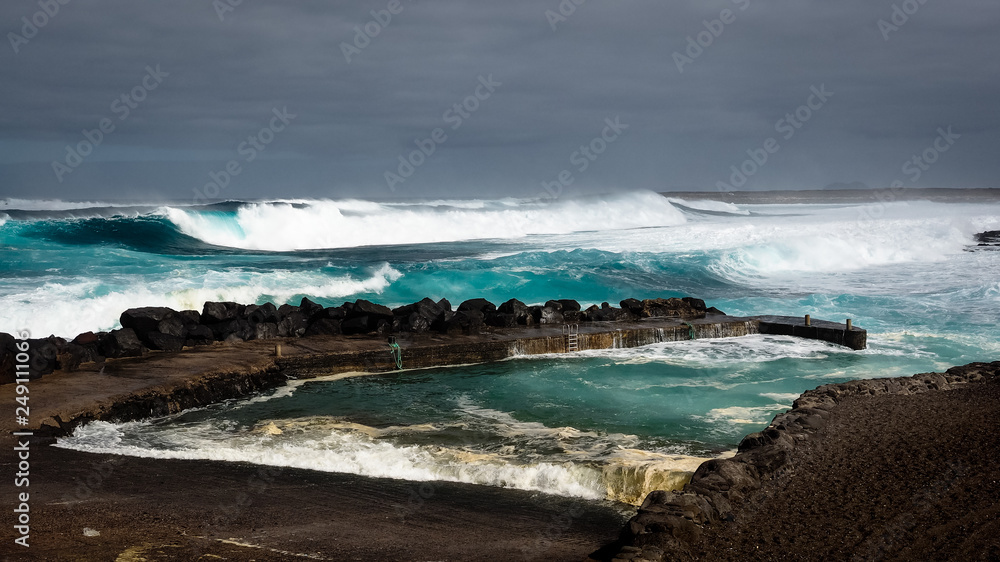 Waves jumping on dock of the fishing cove of La Santa in Lanzarote during a storm.