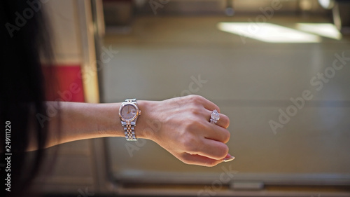 Asian woman checking a time on her left wrist before getting on a train.
