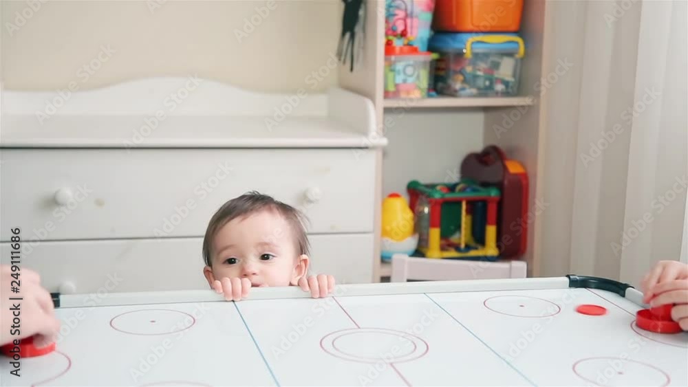 Mom and son enthusiastically playing air hockey and little sister watching them Mom and son enthusiastically playing air hockey and little sister watching them