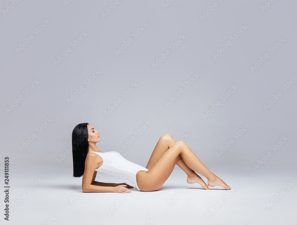 Beautiful fashion model in white swimsuit and hosiery. Young and beautiful woman posing in studio. Beautiful fashion model in white swimsuit and hosiery. Young and beautiful woman posing in studio.