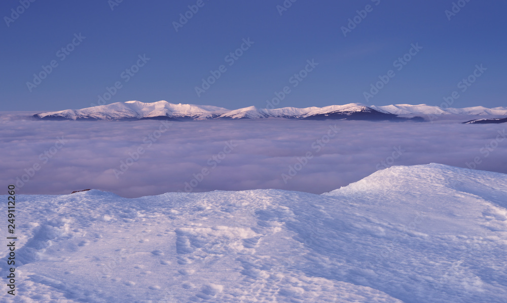 View to snowy mountains range above the clouds