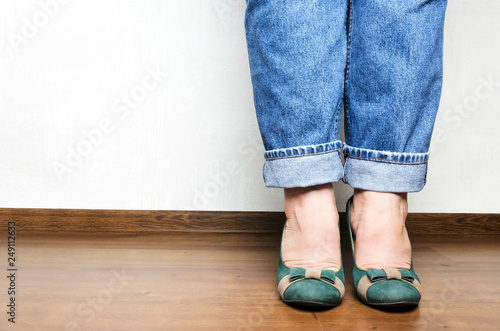 Woman wearing blue jeans and green shoes, standing and waiting in the office.Shot of plus size woman legs, feshion concept