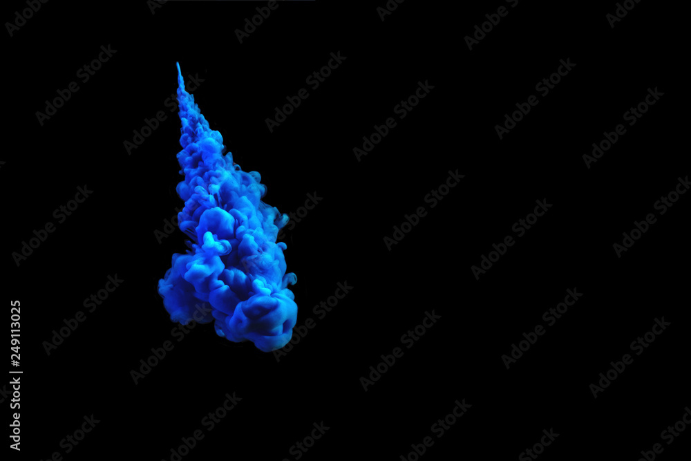 Blue acrylic paint in water isolated on black. Abstract background for design with copy space.