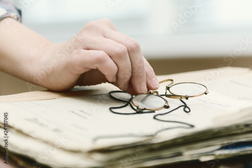 female fingers hold pince-nez over old papers