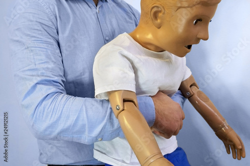 Abdominal thrusts (the Heimlich maneuver or Heimlich manoeuvre) on a simulation mannequin child dummy during medical training Basic Life Support