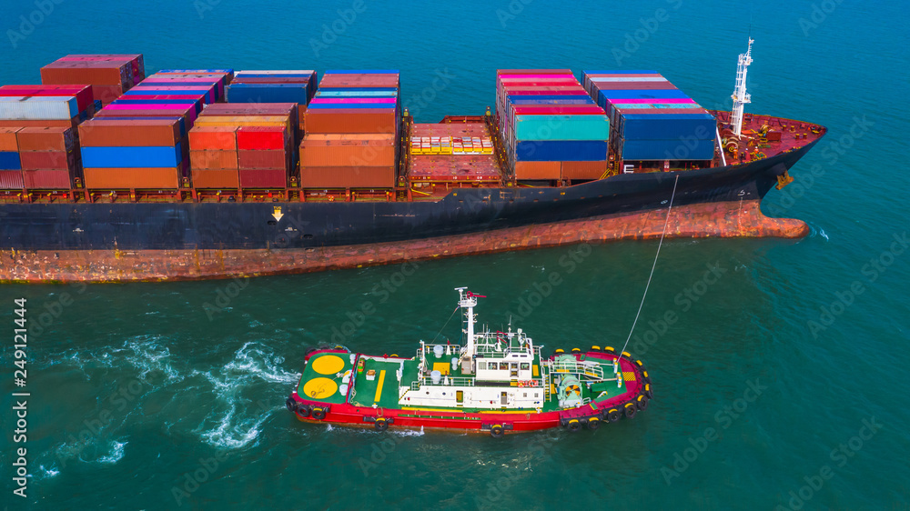 Fototapeta premium Cargo freight ship carrying container and small pilot boat.