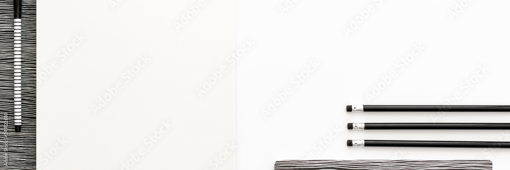 A black and white work desk. Opened notebook, pencils in a row and empty space for text. Copy space and mockup. Panoramic top view. Monochromatic pattern. A black and white work desk. Opened notebook, pencils in a row and empty space for text. Copy space and mockup. Panoramic top view. Monochromatic pattern.