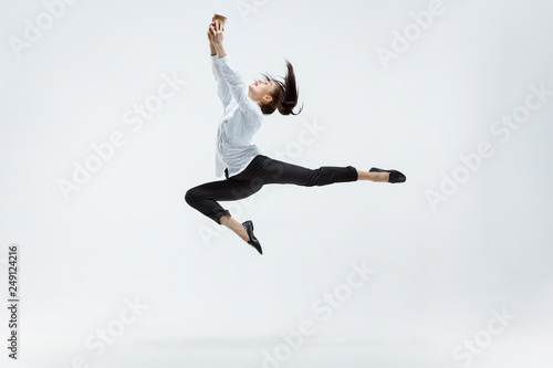 Happy businesswoman dancing and smiling in motion isolated on white studio background. Flexibility and grace in business. Human emotions concept. Office  success  professional  happiness  expression