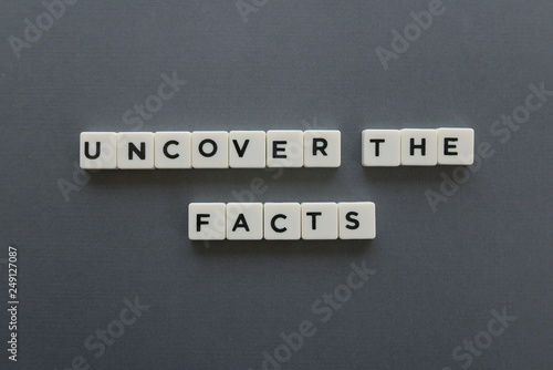 Uncover the facts word made of square letter word on grey background.