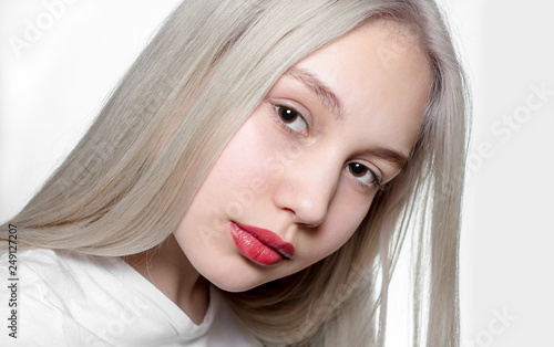 portrait of a young girl with blond hair and red lipstick on the lips on a white background close up