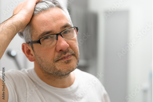 portrait of middle aged gray haired man with glasses in bathroom