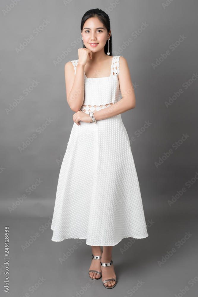 Beautiful woman in white dress portrait in studio, grey background Beautiful woman in white dress portrait in studio, grey background