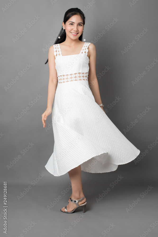 Beautiful woman in white dress portrait in studio, grey background Beautiful woman in white dress portrait in studio, grey background