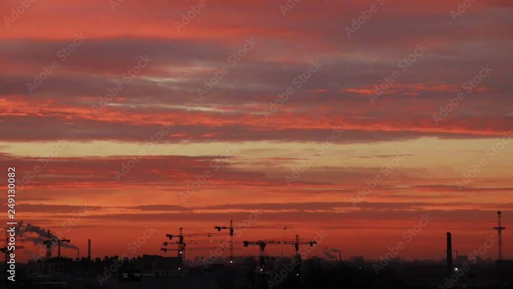Beautiful sunset sky and cranes silhouettes against evening colorful clouds. Camera locked down. Selective focus. Beautiful sunset sky and cranes silhouettes against evening colorful clouds. Camera locked down. Selective focus.