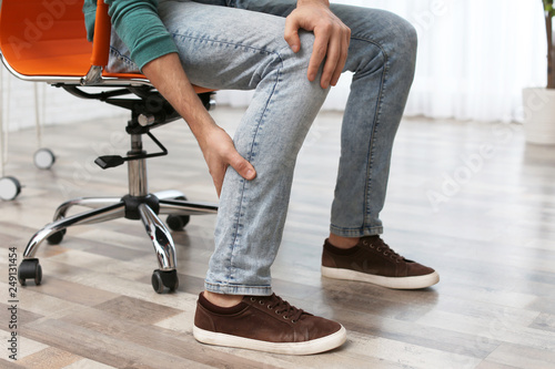 Man suffering from leg pain indoors, closeup © New Africa