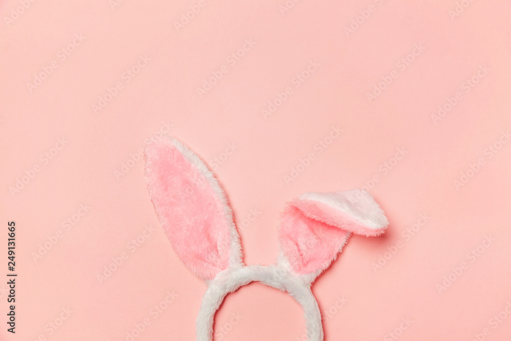 Happy Easter concept. Preparation for holiday. Decorative bunny ears furry fluffy costume toy isolated on trendy pastel pink background. Simple minimalism flat lay top view copy space