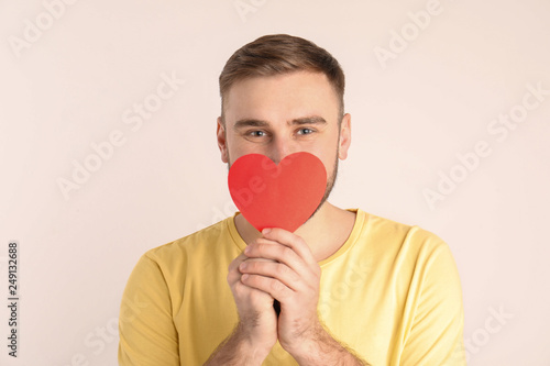 Young man with paper heart on white background © New Africa