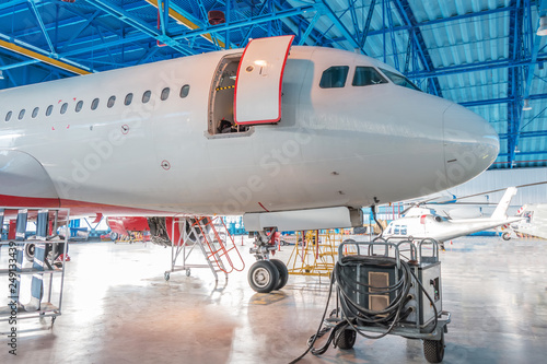 The nose of the aircraft fuselage with open door in the aircraft hangar.