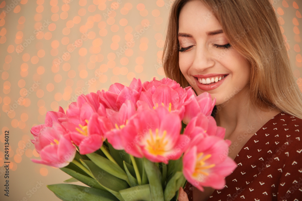 Portrait of smiling young girl with beautiful tulips on blurred background. International Women's Day