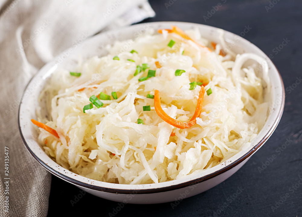 Fermented cabbage. Vegan food. Sauerkraut with carrot and spices in bowl on the dark background. Trend food. Fermented cabbage. Vegan food. Sauerkraut with carrot and spices in bowl on the dark background. Trend food.
