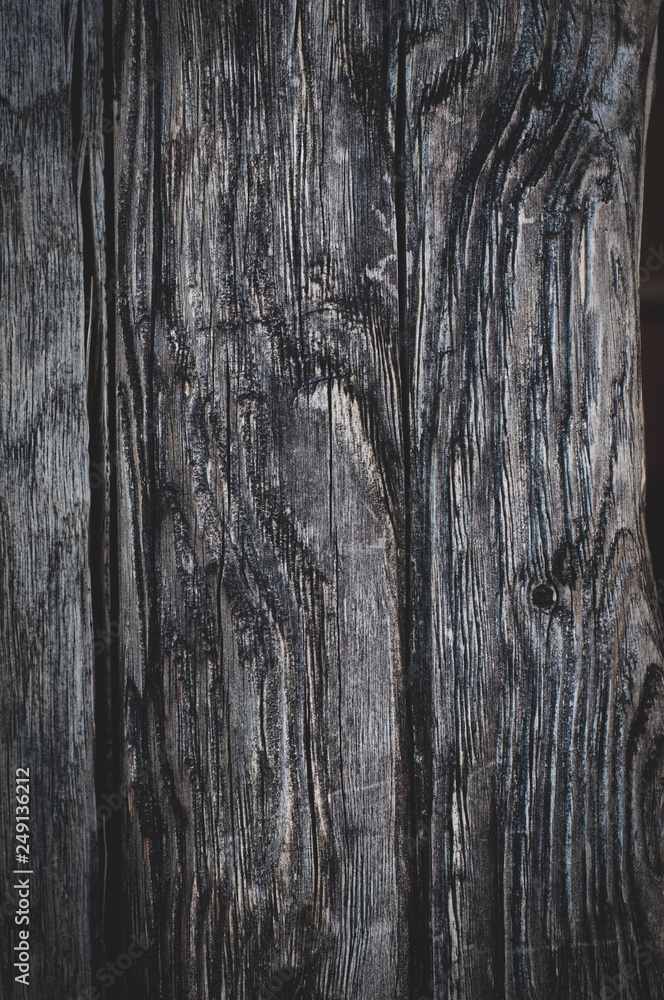 Vertical background of old weathered dark brown cracked wooden gnarled boards close-up Vertical background of old weathered dark brown cracked wooden gnarled boards close-up