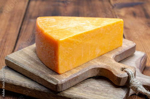 Piece of bright yellow hard cheese cheddar, originating in the English village of Cheddar in Somerset