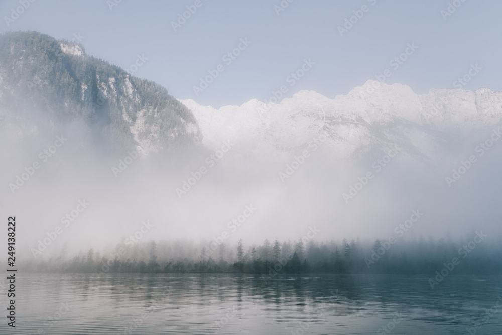 views of forest in the mountain among fog in border of the lake