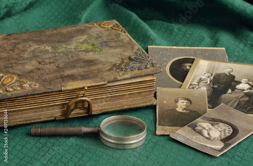 Old photo album and historical photos of family on a green tablecloth. photo